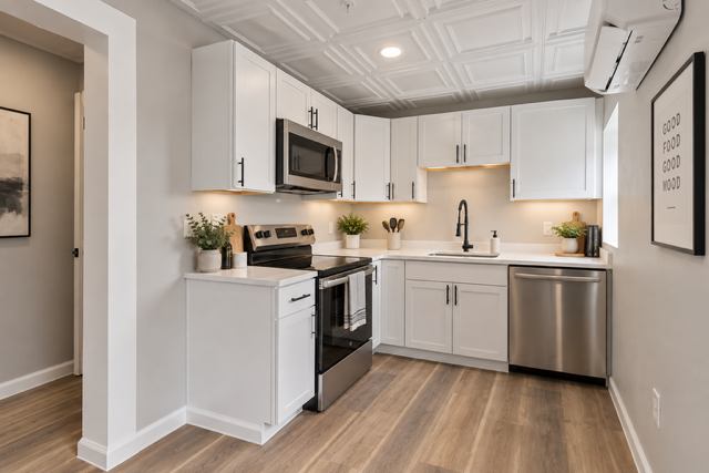 Renovated kitchen at Ivy Gardens with white shaker cabinetry, stainless-steel appliances and a decorative tin ceiling